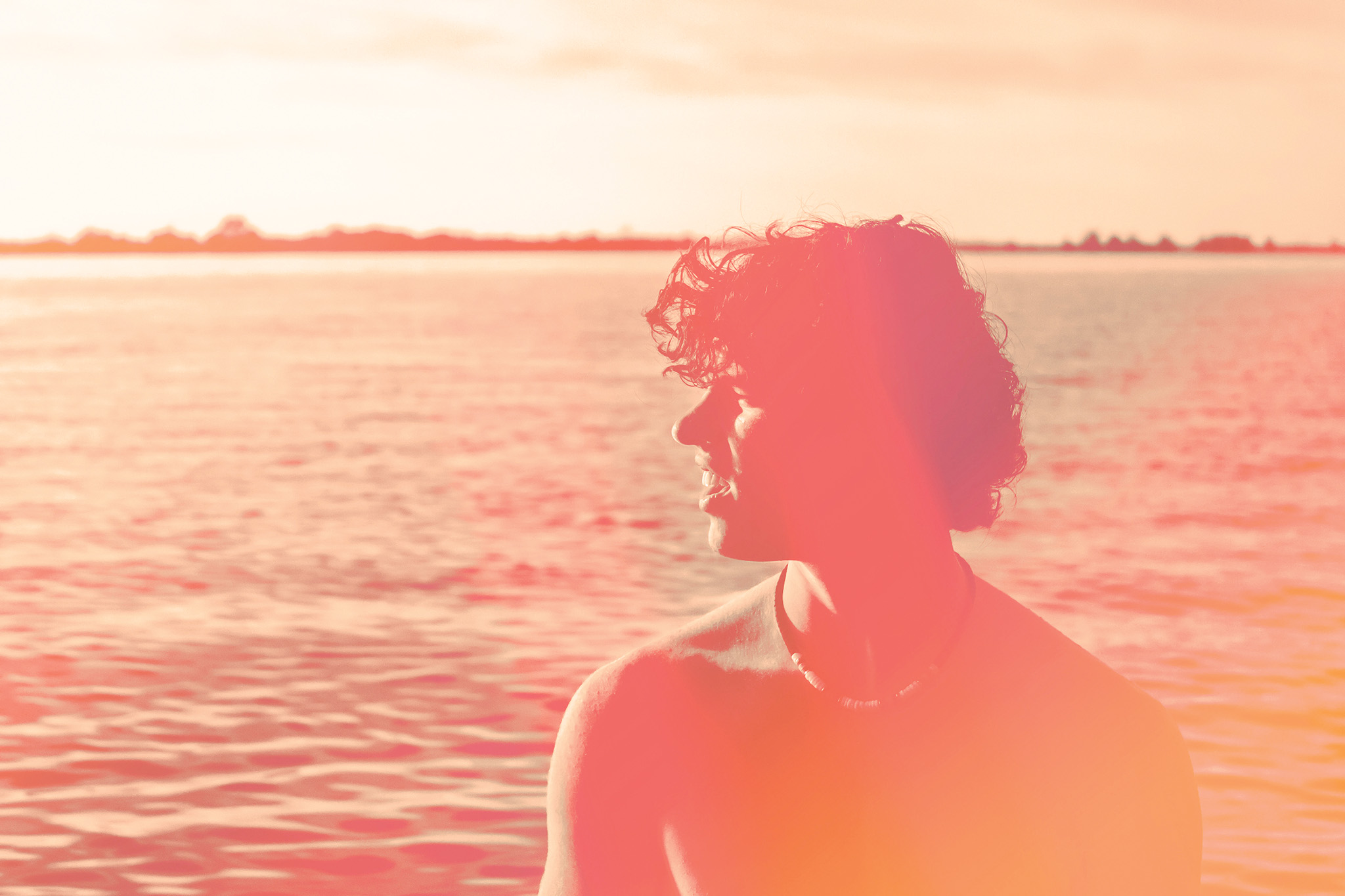 This acts as an example of an image after proper editing. It has had it's colours heavily edited to be made up of pinks, peaches and oranges. It depicts a teen at a lake with sun shining on him.