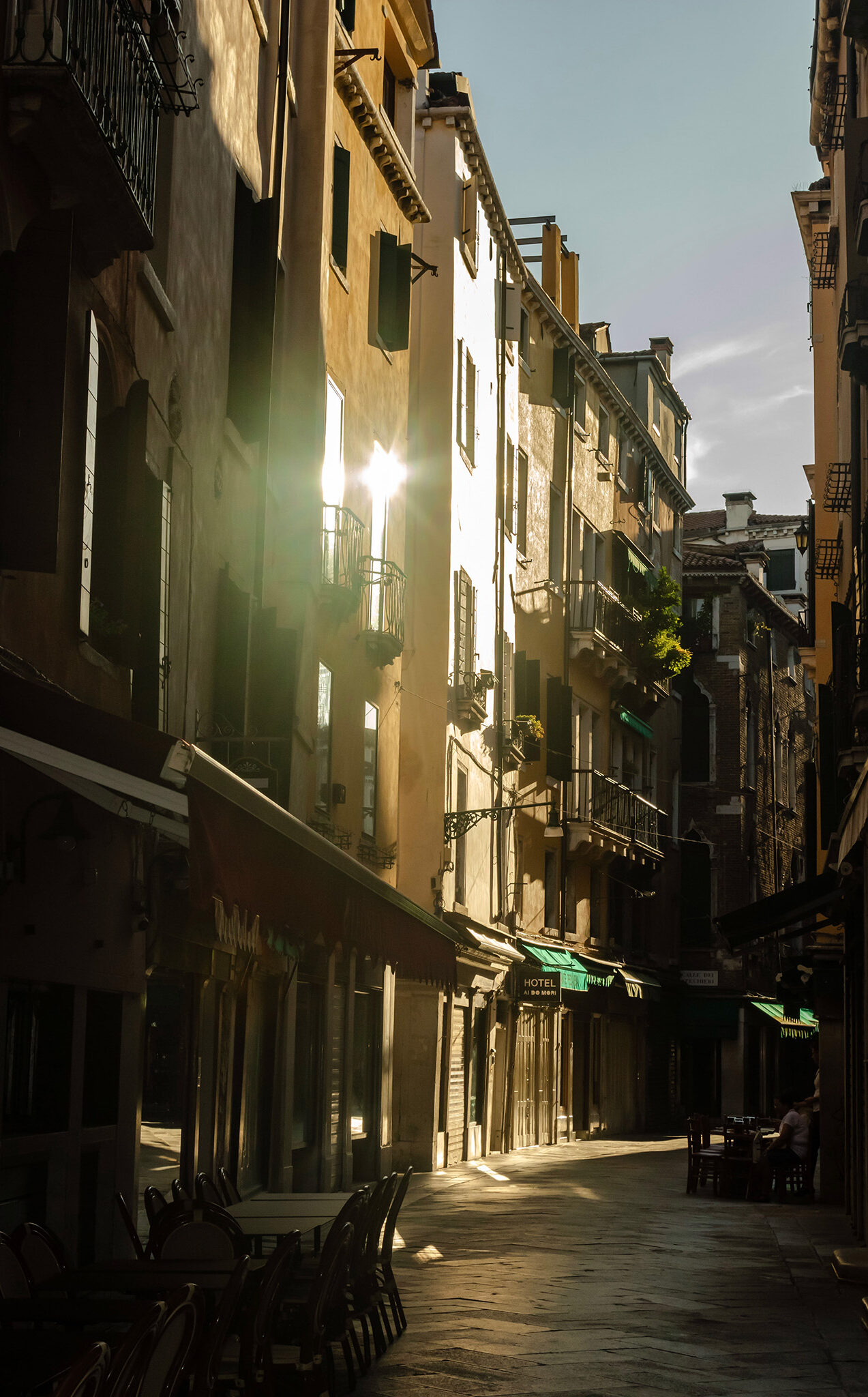 Winding street in Venice with morning sunlight gleaming off the apartments windows onto the street below.